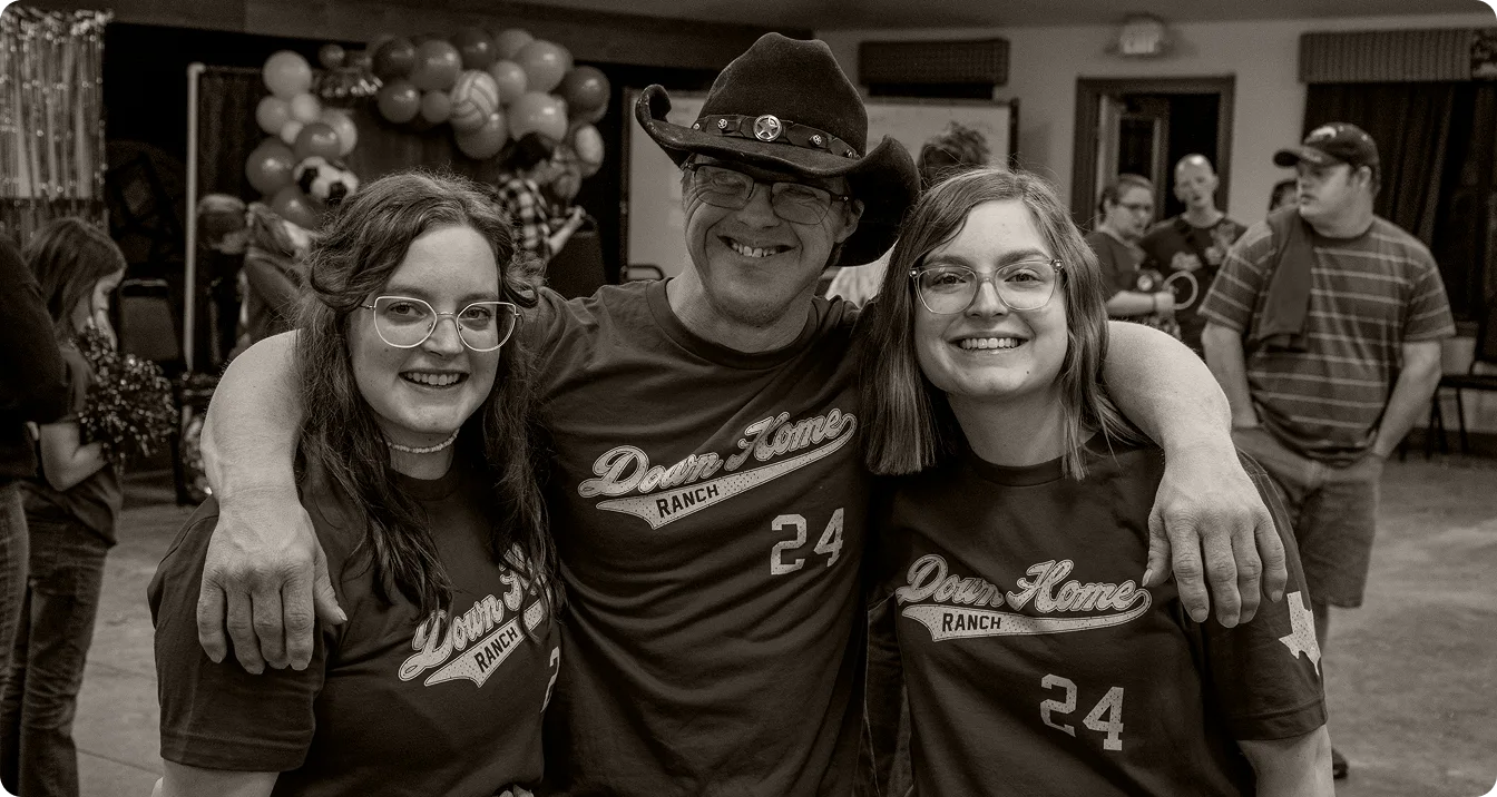 An image of a camper wrapping his arms around two people